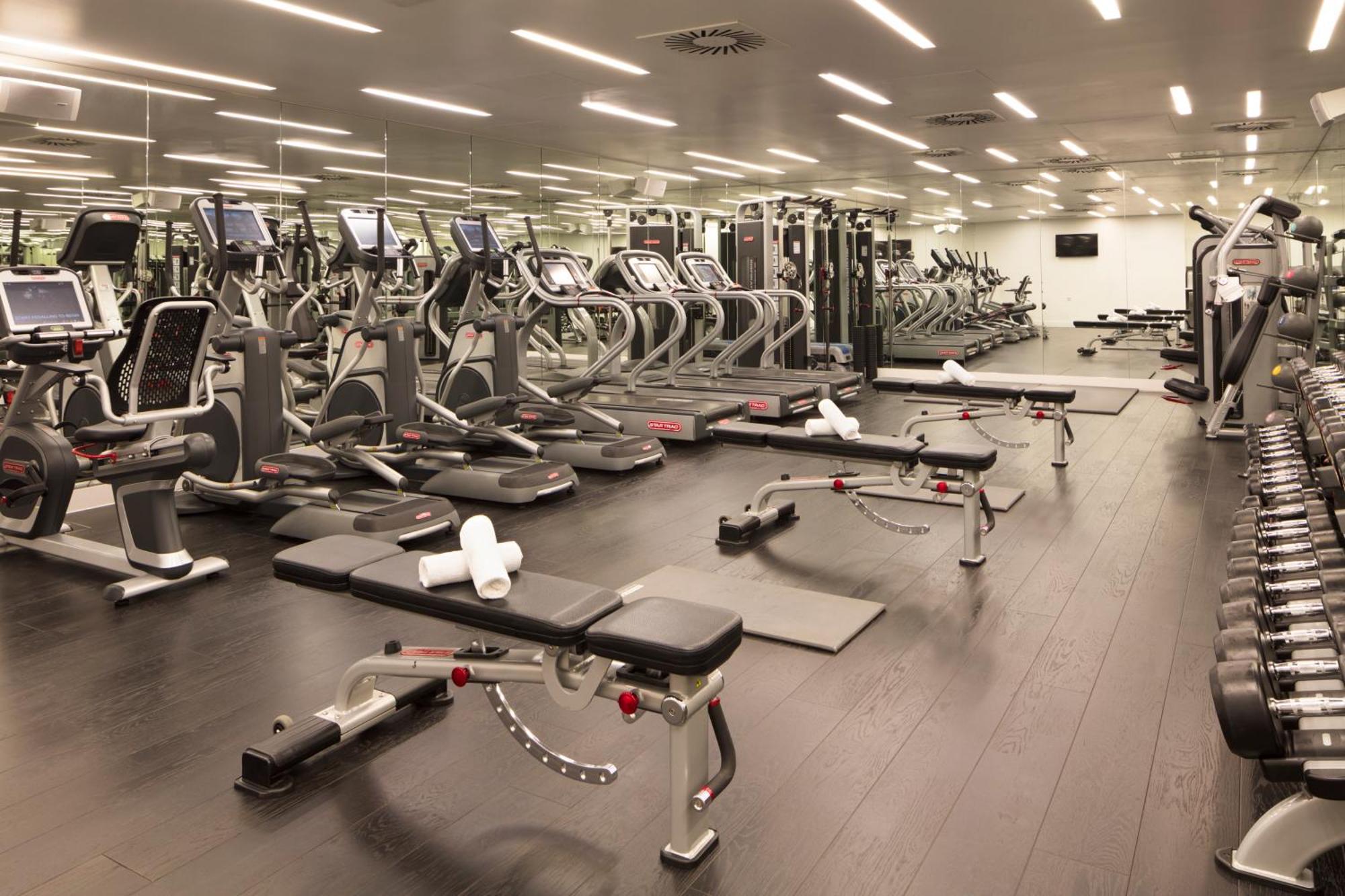 Sea Containers London Hotel Exterior photo The photo shows a modern gym interior. There are several exercise machines arranged neatly, including treadmills and weight training machines. The floor is dark, and the gym is well-lit with overhead lighting. In the foreground, there are benches for