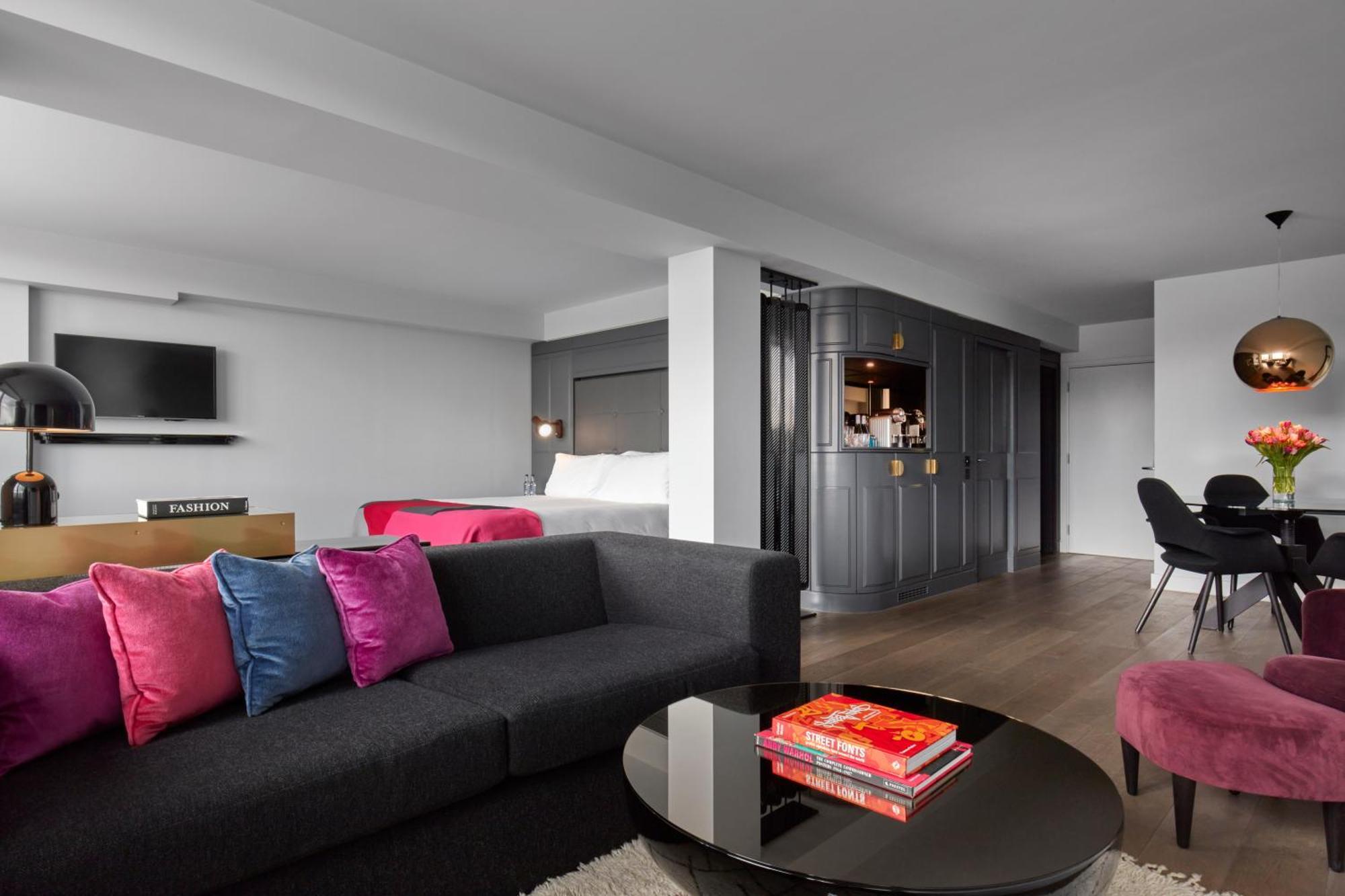 Sea Containers London Hotel Exterior photo The photo shows a modern and stylish living space. In the foreground, there is a dark gray sofa adorned with colorful pink and blue pillows. A circular coffee table sits in front of the sofa, with a few books stacked on it. 

In the background, there