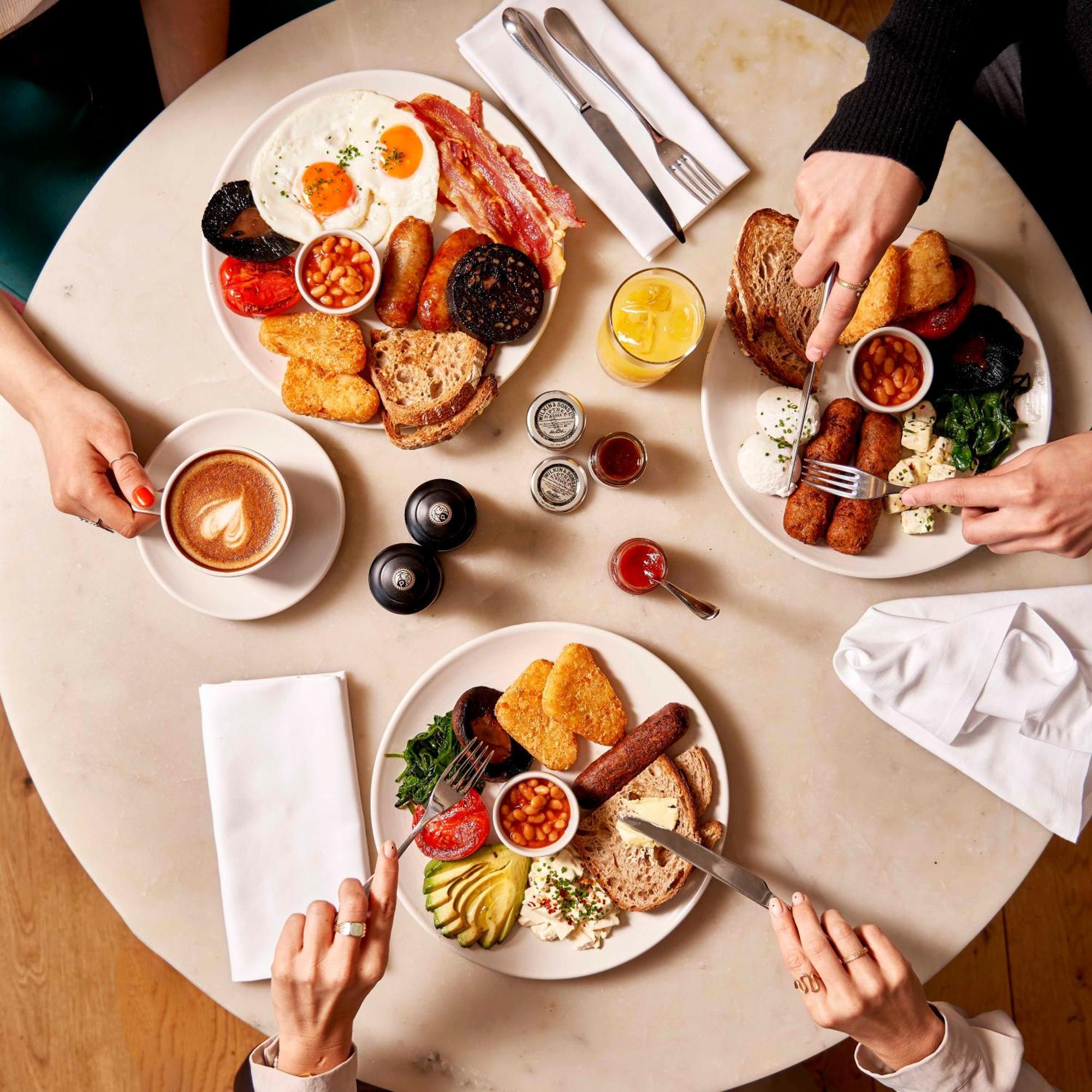 Sea Containers London Hotel Exterior photo The photo shows a beautifully set table with three plates of food, each featuring a variety of breakfast items. The dishes include:

1. **Main Plates**: Each plate contains a hearty breakfast spread, which includes items like eggs, bacon, sausages, b