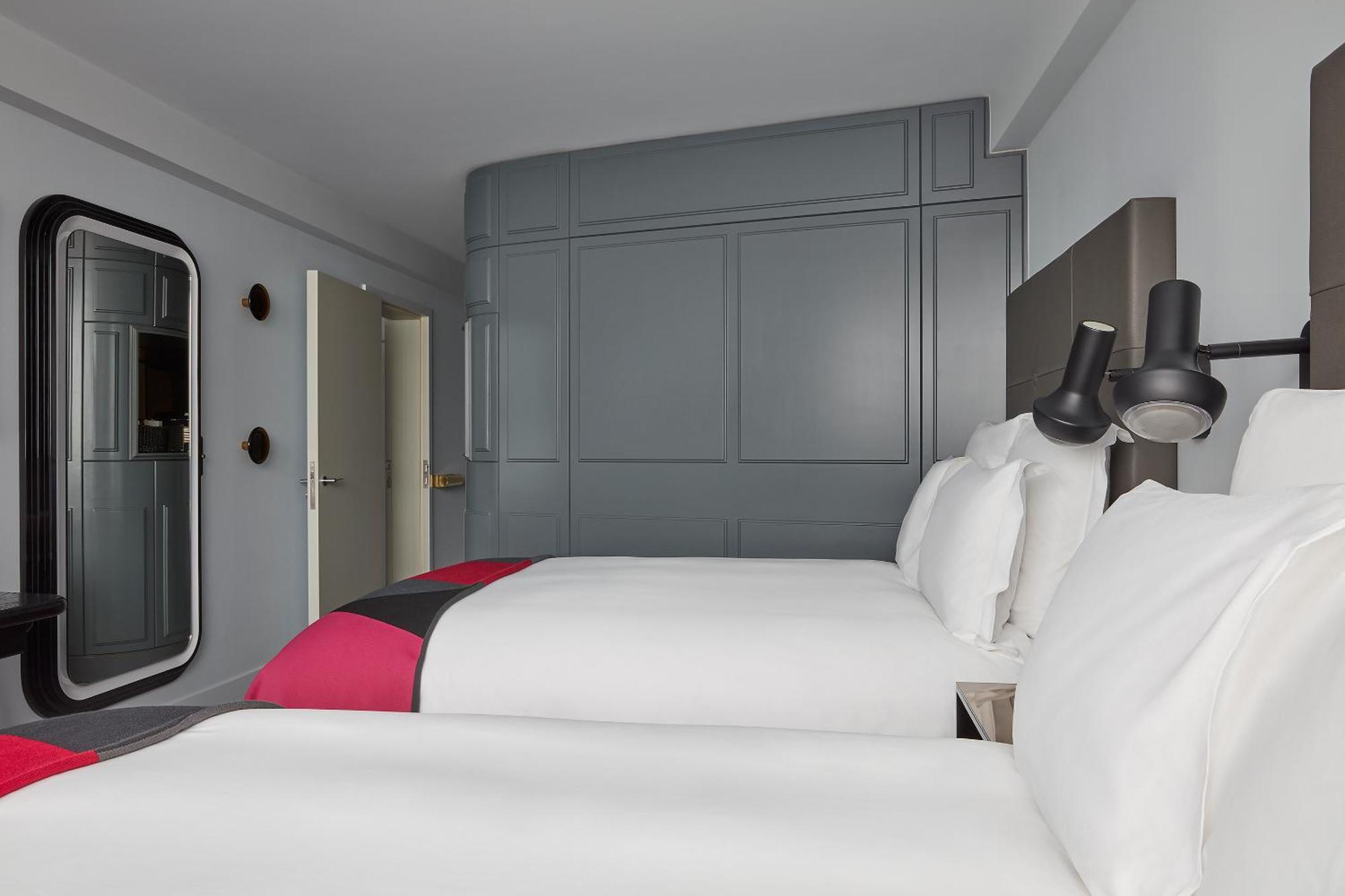 Sea Containers London Hotel Exterior photo The photo shows a hotel room with a contemporary design. It features two beds with white linens, complemented by vibrant pink and gray accents. The walls are painted in a soft gray color, creating a modern and minimalistic aesthetic. There is a styli