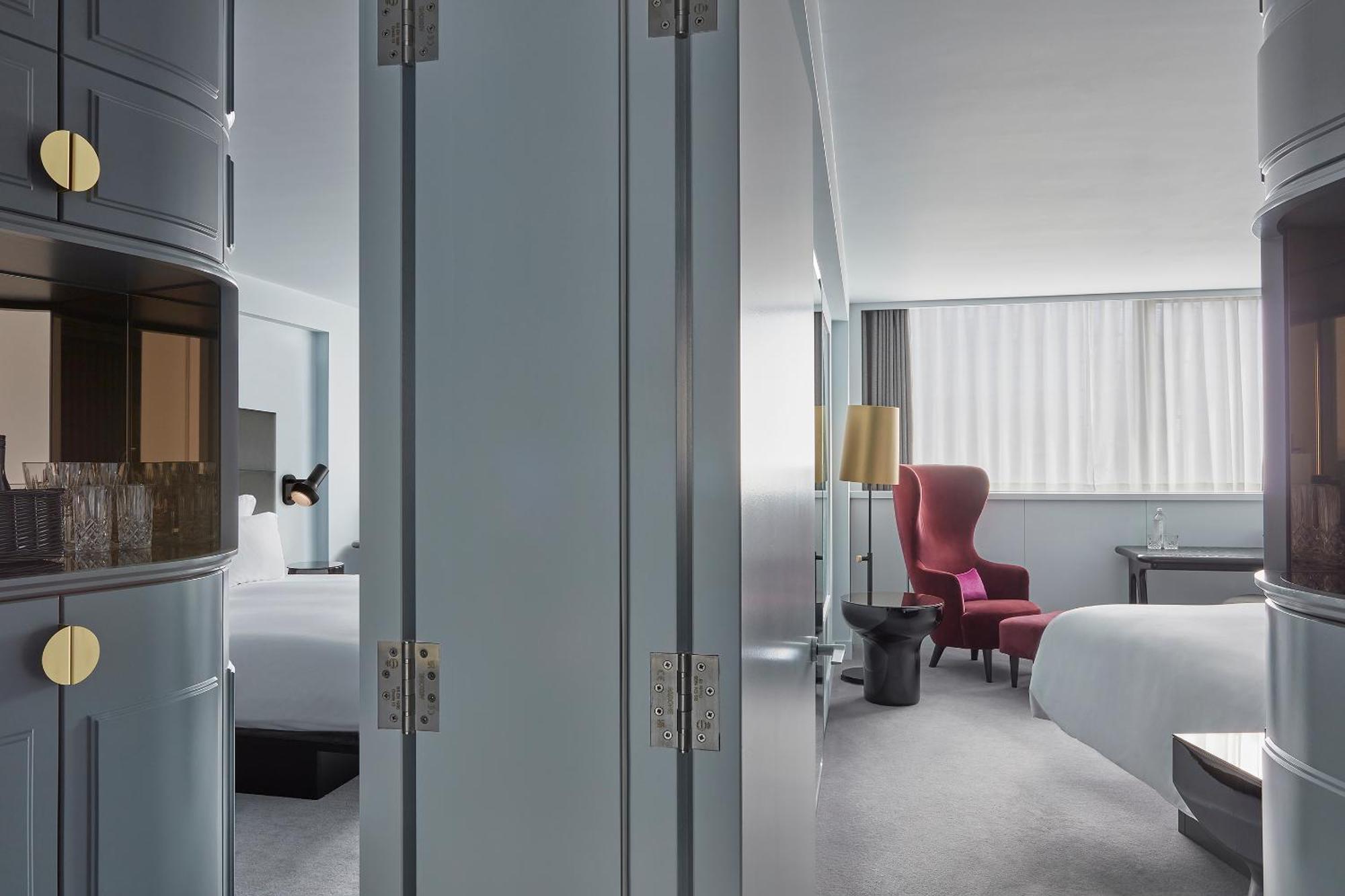 Sea Containers London Hotel Exterior photo The photo shows an interior space that appears to be a modern hotel room. The room is divided by a pair of large, grey doors that are slightly ajar. To one side, there are elements that hint at a welcoming, spacious ambiance, such as a bed with white