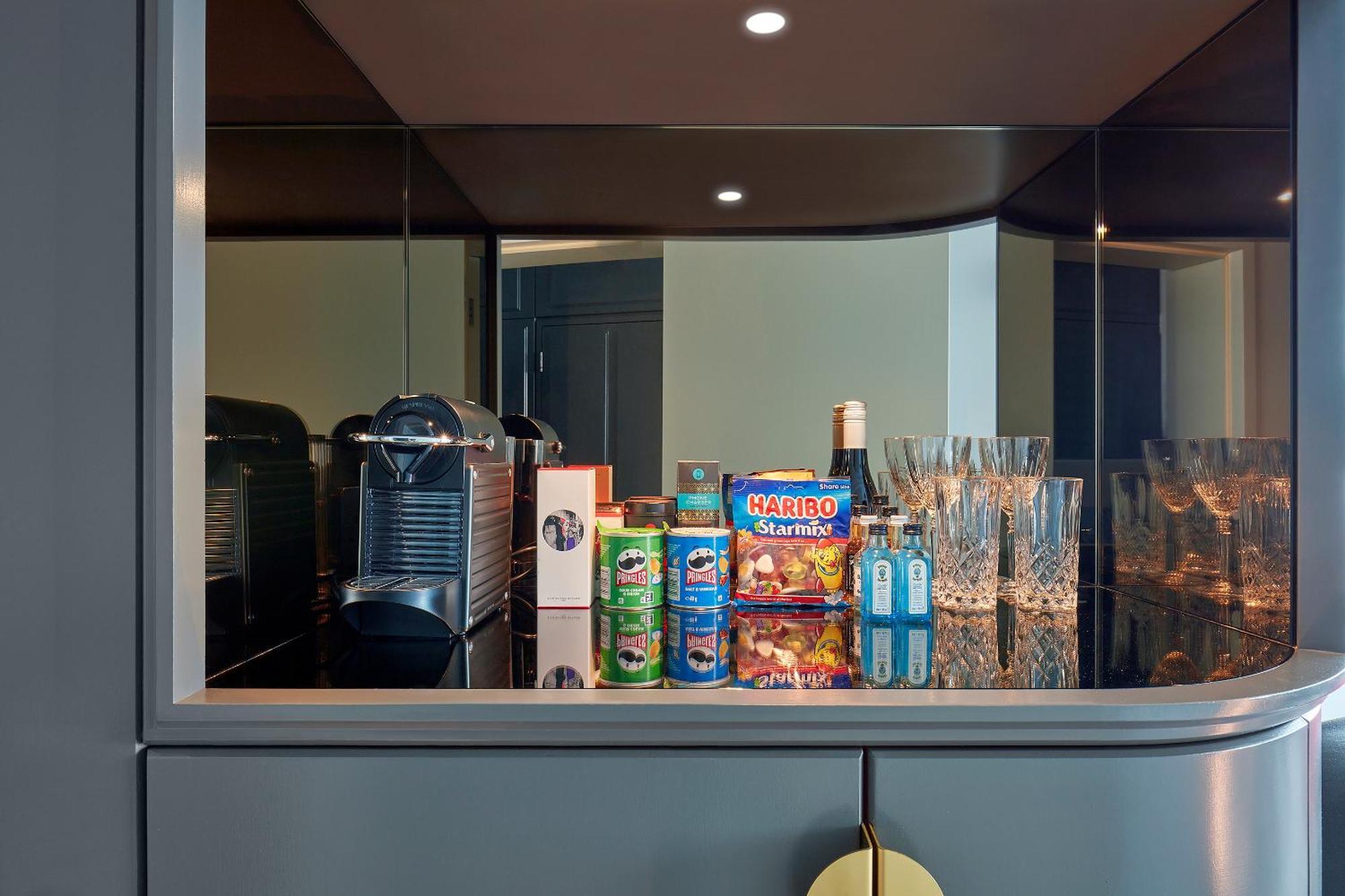 Sea Containers London Hotel Exterior photo The photo shows a sleek, modern minibar or kitchenette area. It features a coffee machine on the left side and a variety of items displayed neatly. There are several containers, including cans and boxes of snacks, such as a brightly colored box label