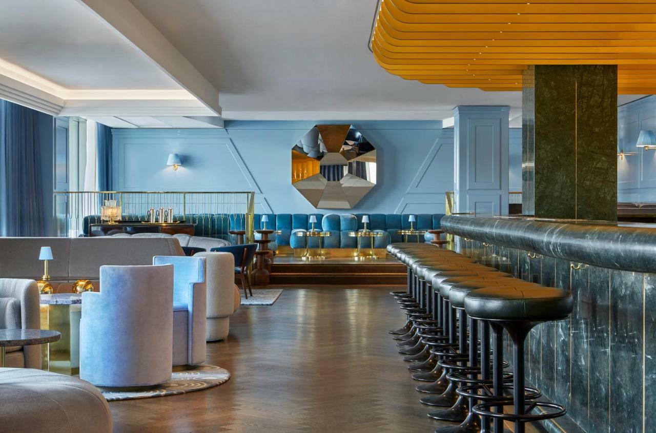 Sea Containers London Hotel Exterior photo The photo displays a modern and stylish bar or lounge area. The interior features a combination of soft blue walls and elegant furnishings. There are circular seating arrangements in light colors, creating a cozy atmosphere. A long bar counter made o