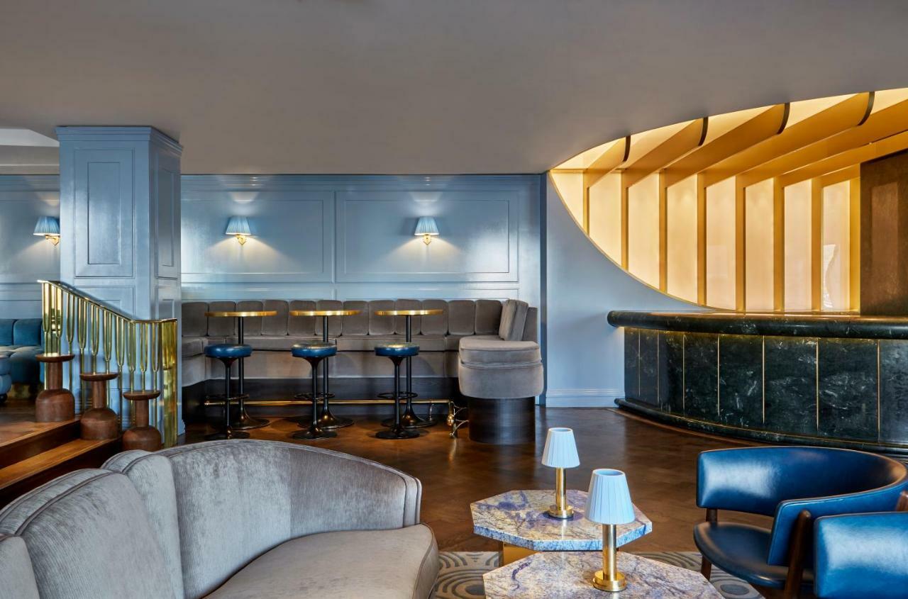 Sea Containers London Hotel Exterior photo The photo shows an elegantly designed interior space, likely a bar or lounge. The area features a modern seating arrangement with a mix of comfortable sofas and bar stools. The walls are painted in a soft blue color, complemented by wooden accents an